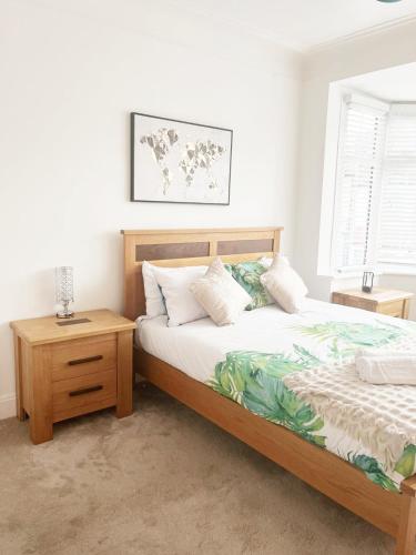 a bedroom with a bed with a wooden frame and a table at Large 3 Bedroom Home, Sleeps 7, Ideal for Families & Contractors, Long-Stay Friendly, Hosted by Clark Property Estates in Southend-on-Sea