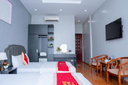 um quarto com uma cama branca e uma televisão em Clover Hotel em Hanói