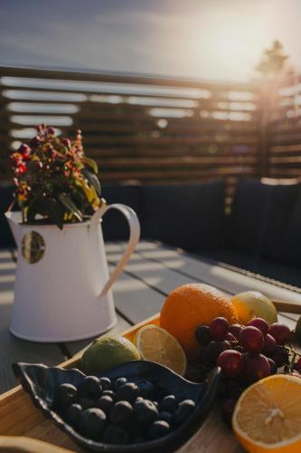 a table with a plate of fruit and a pitcher of flowers at Chce się być in Ślesin