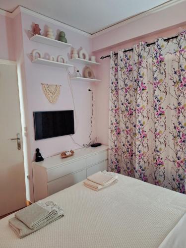 a bedroom with a bed and a tv and a window at Dani's boho home in Mesolongion