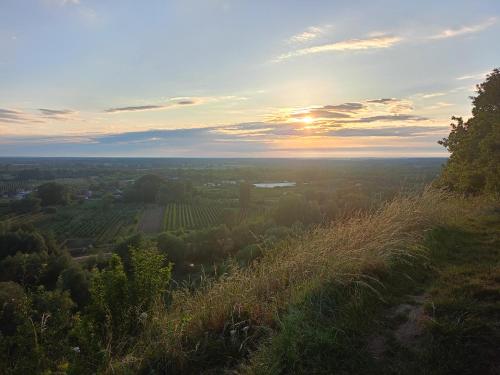 a view of a field with the sun setting on a hill at Siedlisko Panorama na Koncu Swiata - Całoroczny domek in Podgórz