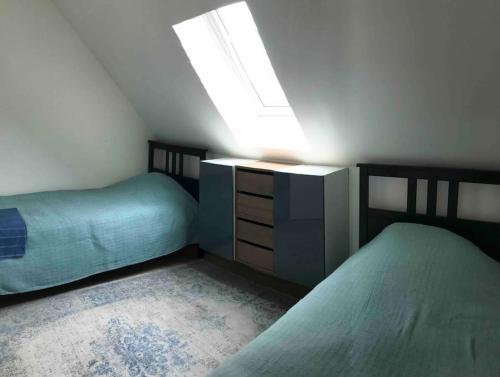 une chambre mansardée avec deux lits et une lucarne dans l'établissement Maison mer jardin 4 personnes, à Houlgate