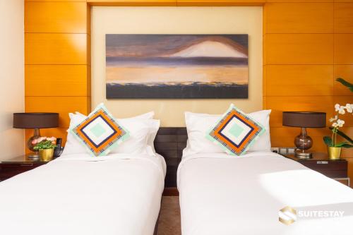 two white beds in a room with a painting at Fashion avenue Dubai Mall -The Residence in Dubai