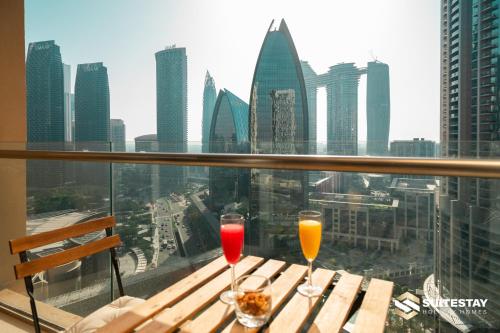 two wine glasses sitting on a table with a view of the city at Fashion avenue Dubai Mall -The Residence in Dubai