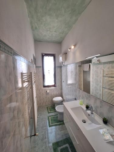 a bathroom with a sink and a toilet and a window at La casa dì Nonno in Pelago