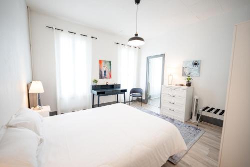 a white bedroom with a bed and a desk at Villa Vichéia - Appartement 23 in Vichy