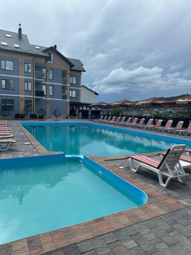 a large swimming pool with lounge chairs and a hotel at Guest House Zatyshnyi Dvir in Bukovel