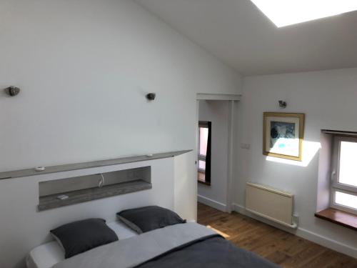 a white bedroom with a bed and two windows at la cerisiere in Bessenay
