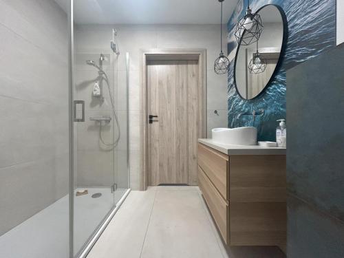 Un baño con ducha, lavabo y espejo. en APARTAMENTY Wakacyjna 53 Dziwnówek, Wrzosowo, en Dziwnówek