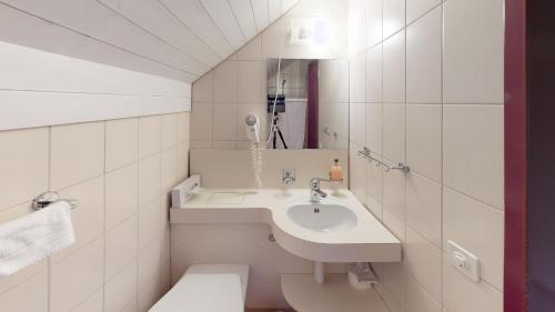 a white bathroom with a sink and a toilet at Hotel-Restaurant Seegarten-Marina in Spiez