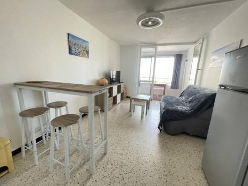 une cuisine avec une table et des tabourets dans une pièce dans l'établissement Cap d' Agde - Studio-Cabine - 100 m Plage du Môle - classé 1 étoile, au Cap d'Agde
