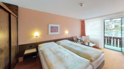 a hotel room with a bed and a window at Hotel-Restaurant Seegarten-Marina in Spiez