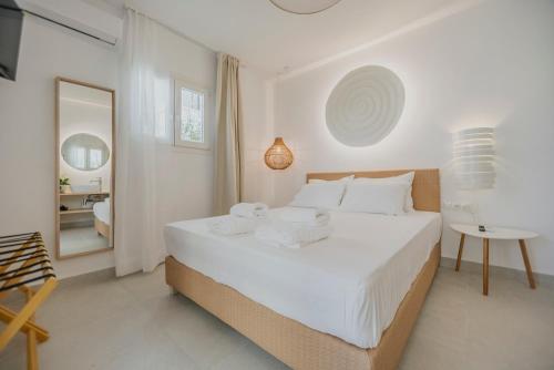 - une chambre blanche avec un grand lit et un miroir dans l'établissement Golden Bird's, à Naxos Chora