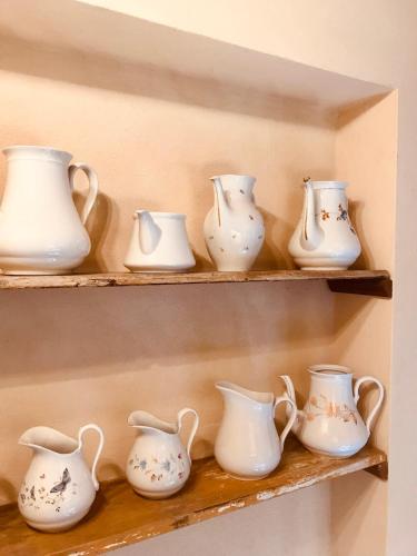 a row of white vases and pitchers on shelves at Agriturismo La Palazzina in Palaia