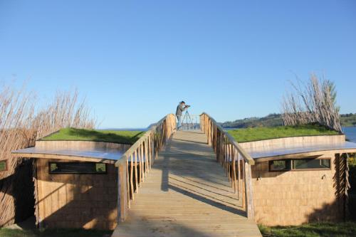 a wooden bridge with a person standing on it at Refugio Pullao in Quilquico