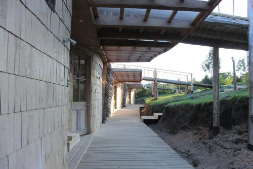 a building with a wooden walkway next to a building at Refugio Pullao in Quilquico