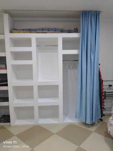 a closet with white shelves and a blue curtain at Квартира-студия с видом на море in Ureki