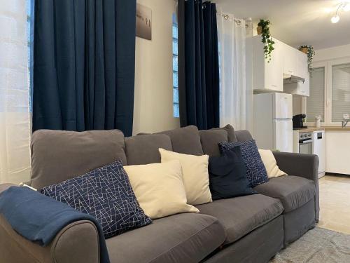 un canapé gris avec des coussins bleus et blancs dans un salon dans l'établissement Résidences des pruniers proche Paris-Orly, à Villeneuve-Saint-Georges
