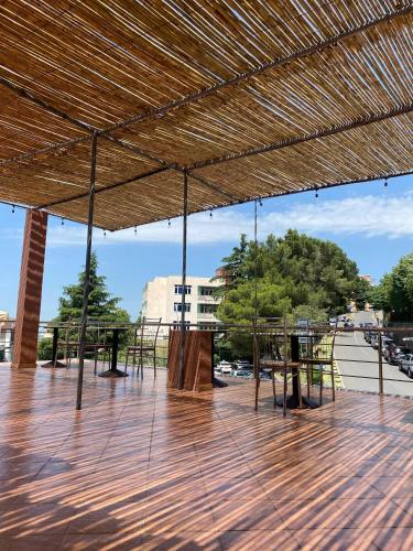 a patio with tables and chairs and a straw roof at Kruja Townscape Rooms in Krujë