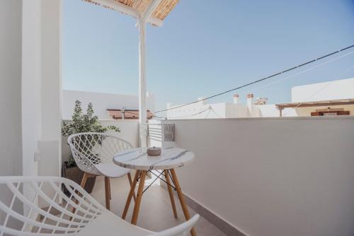 a balcony with white chairs and a table and an umbrella at Golden Bird's in Naxos Chora