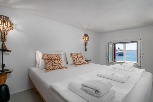 a white bedroom with a large white bed with towels on it at Vitalis Residences - Haven Suites in Adamas