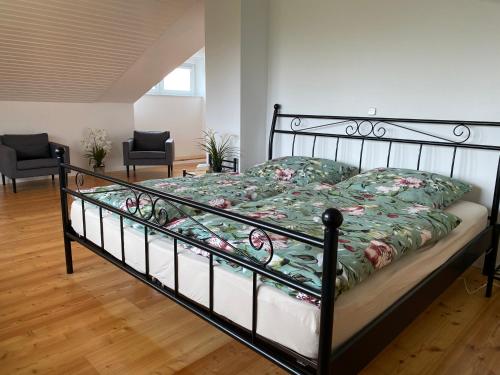 a bed with a black frame with a floral comforter at Ferienwohnung Ebersburg in Rabennest