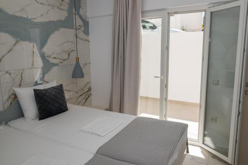 a bedroom with a white bed and a stone wall at Katerina Roza Studios - Heartfelt Hospitality in the City in Naxos Chora