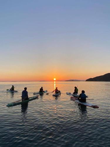 a group of people kayaking on the water at sunset at nagi-setouchi in Kure