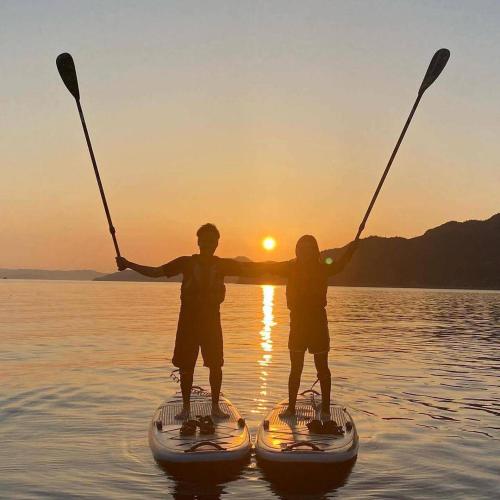 two people are standing on paddle boards in the water at nagi-setouchi in Kure