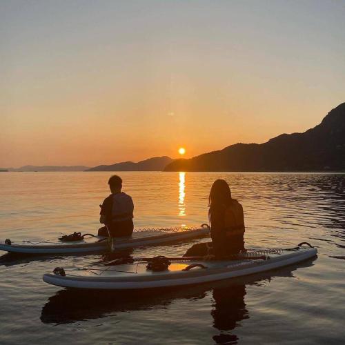 two people sitting on a kayak in the water at sunset at nagi-setouchi in Kure