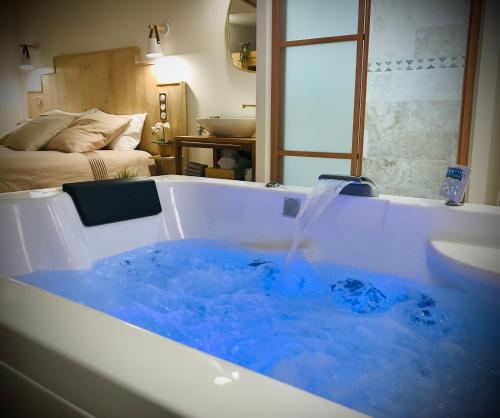 a bath tub filled with blue water in a room at Suite Spa et Sauna de Cogny in Cogny