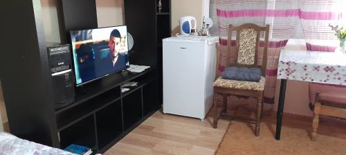 a living room with a tv and a chair and a television at Klara Rooms in Gevgelija