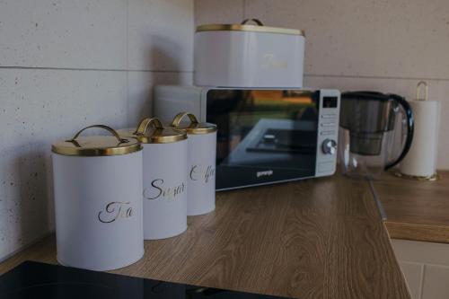 three mugs sitting on a counter next to a microwave at Chce się być in Ślesin