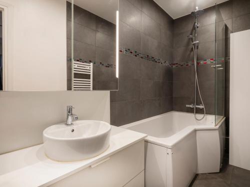 une salle de bain blanche avec un lavabo et une douche dans l'établissement Paris Arc de Triomphe Residence, à Paris