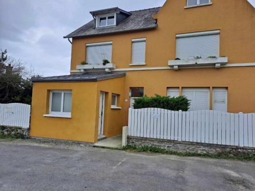 a yellow house with a white fence in front of it at Appartement 2-3 personnes résidence les mimosas Port-Mer Cancale in Cancale