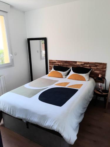 a bedroom with a large bed with white and orange pillows at Appartement 2-3 personnes résidence les mimosas Port-Mer Cancale in Cancale