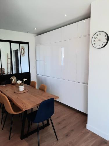 une salle à manger avec une table en bois et une horloge dans l'établissement Appartement 2-3 personnes résidence les mimosas Port-Mer Cancale, à Cancale