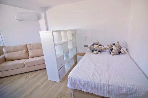a white bedroom with a bed and a couch at Plazamar 6 Jose in Torre del Mar