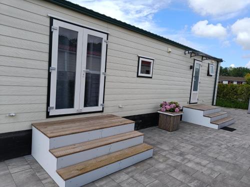 a house with stairs leading up to a patio at Cozy chalet near Amsterdam at Camping Venhop in Berkhout