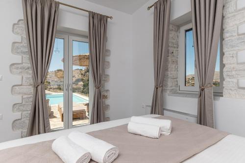 a bedroom with a bed with a view of a pool at Marble Arch Apartments in Naxos Chora