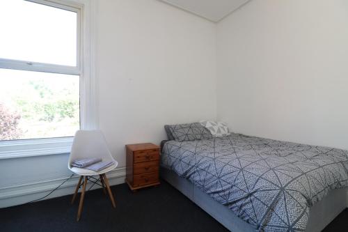 a bedroom with a bed and a chair and a window at Pebbles guest house room 5 in Southampton