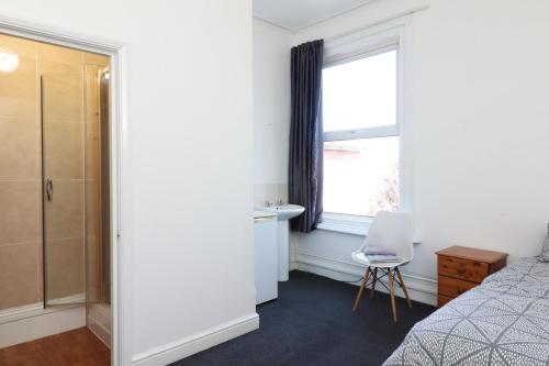 a bedroom with a bed and a window and a chair at Pebbles guest house room 5 in Southampton