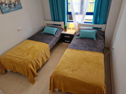 two beds in a small room with blue curtains at Apartment Bella Vista with sea view in Dehesa de Campoamor