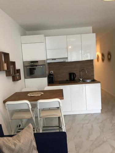 une cuisine avec des armoires blanches et une table et des chaises dans l'établissement Appartement 1 minute de la promenade des Anglais, à Nice