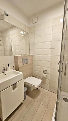 ein weißes Bad mit einem WC und einem Waschbecken in der Unterkunft Apartament przy Porcie w Krynicy Morskiej in Krynica Morska