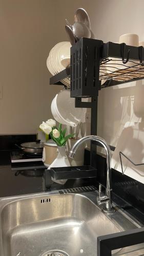 a kitchen counter with a sink and plates on a shelf at FLEXI Staycation in Manila