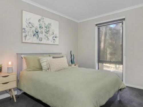 a white bedroom with a bed and a window at Sawmill Chalet - Located base of Mt Buller in Merrijig