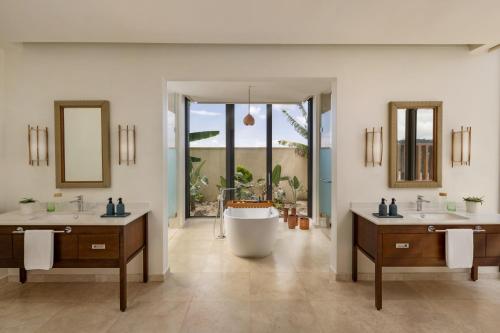 a bathroom with two sinks and a bath tub at Six Senses La Sagesse 