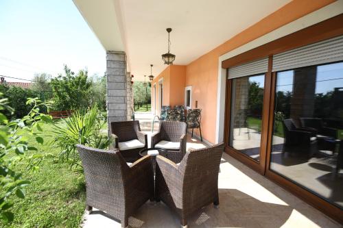 an outdoor patio with wicker chairs and glass doors at Lush Garden Hideaway FAMA near Portoroz in Sečovlje