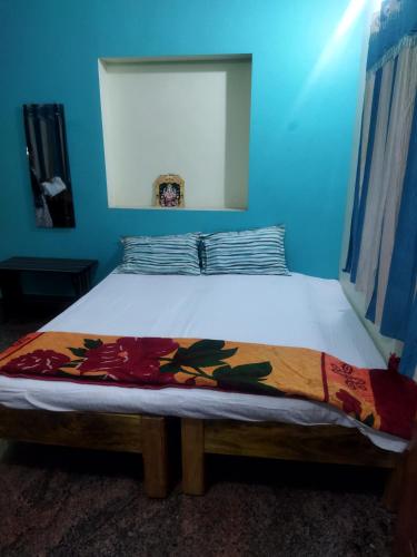 a bed in a room with a blue wall at Sahana Villa in New Hampi